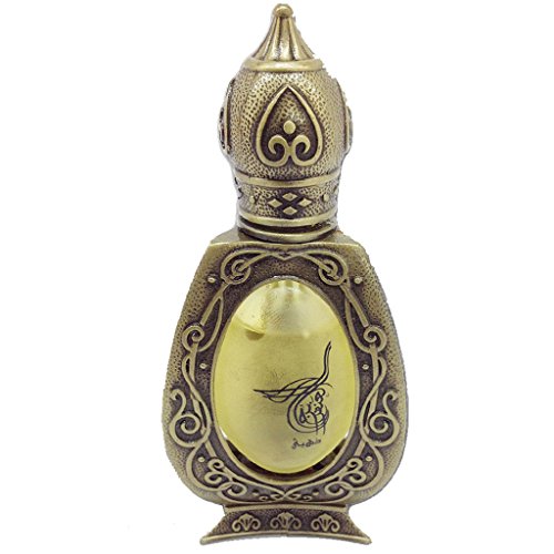 Ornate antique brass perfume bottle with intricate scrollwork and a window displaying yellow oil and Arabic calligraphy.