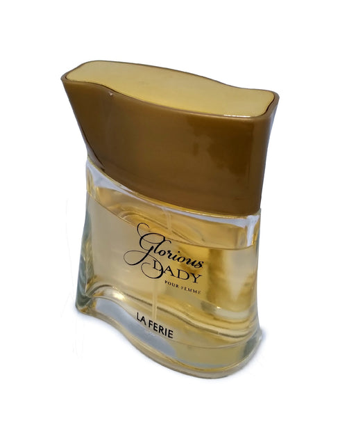 La Ferie Glorious Dady Pour Femme perfume in a clear glass bottle with a large, wavy gold cap.