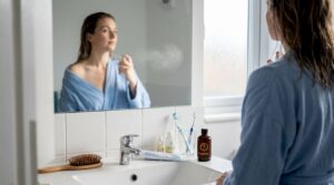 Woman applying perfume in home bathroom