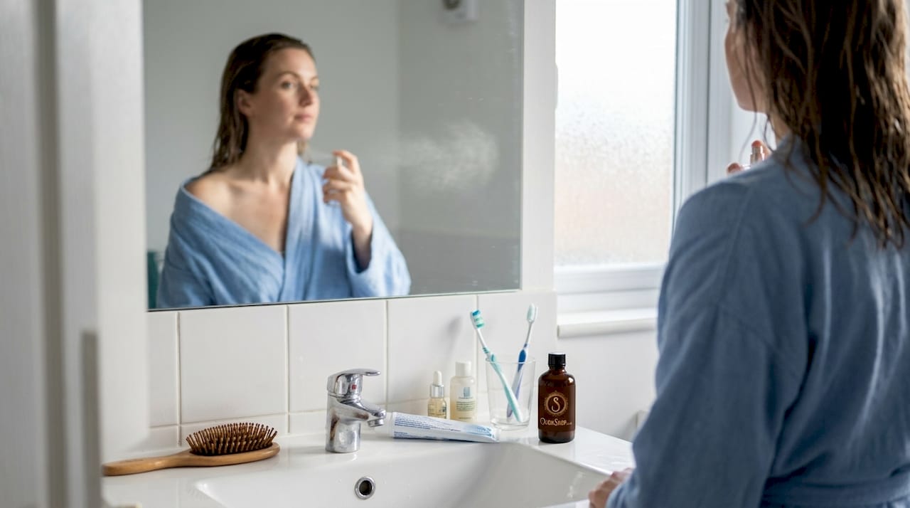 Woman applying perfume in home bathroom